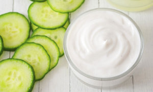 Bowl of skin cream and cucumber slices