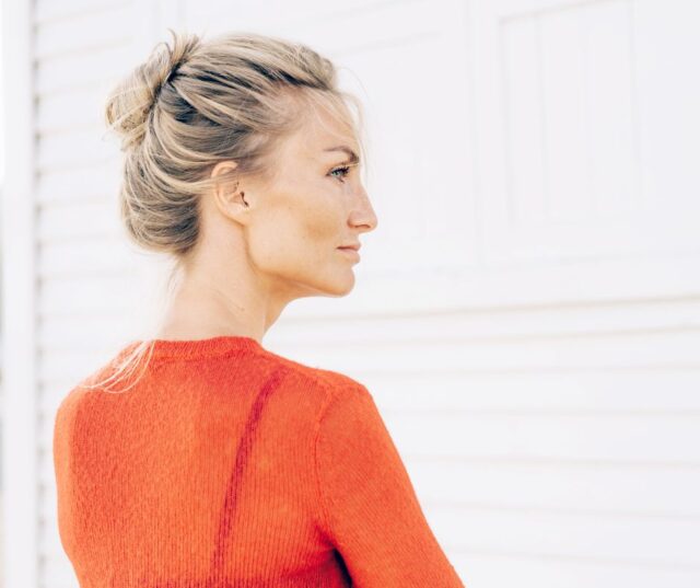 Women profile view wearing a red shirt with a sculpted jawline.